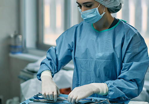 A surgical assistant arranging medical instruments in an operating room.