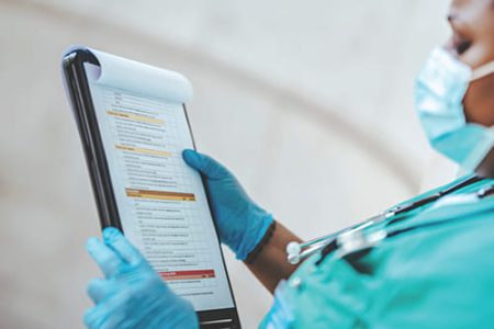 A medical professional in scrubs reads a clipboard with a checklist A medical professional in scrubs reads a clipboard with a checklist