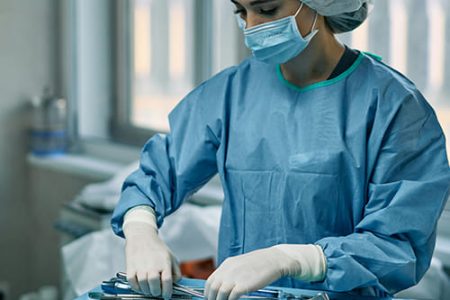 A surgical assistant arranging medical instruments in an operating room. A surgical assistant arranging medical instruments in an operating room.